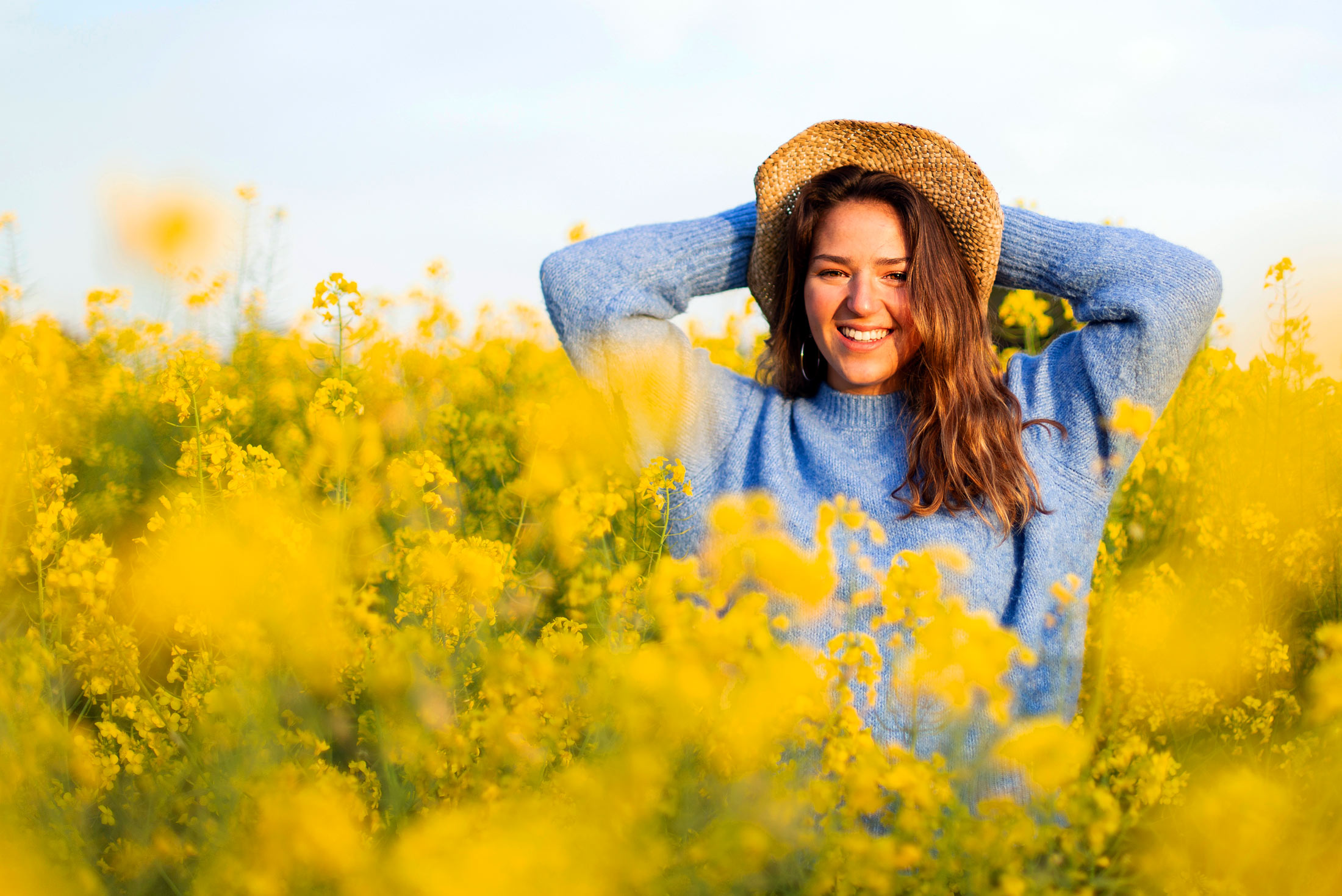 Frau-mit-Hut-in-einer-gelben-Blumenwiese-Bild